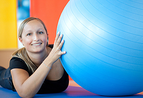 Eine Patientin macht eine Übung mit einem Gymnastikball.
